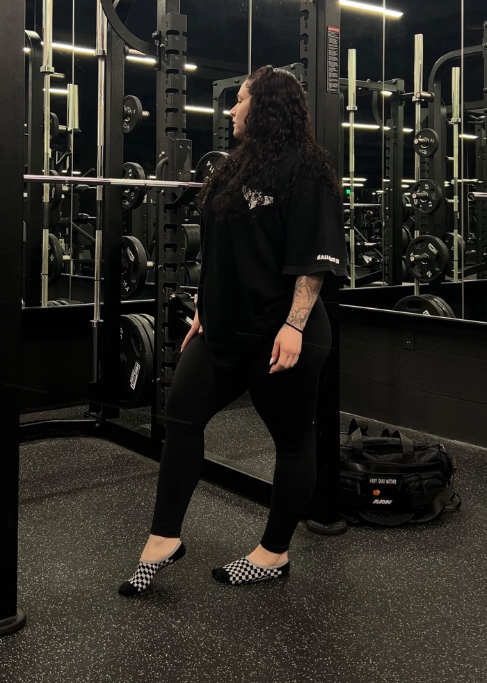 Coach in black workout outfit standig in the gym.