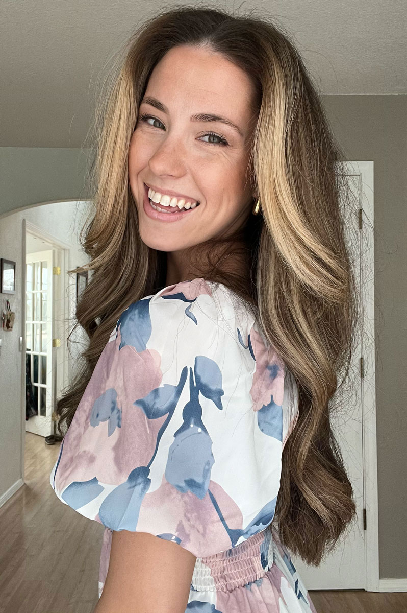 The coach is smiling while wearing the flower printed dress.