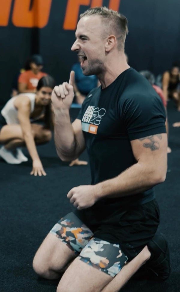 coach on his knees giving insructions to his clients in the gym.