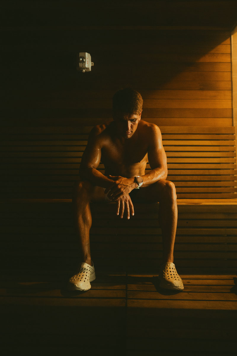Coach is posing topless while drinking.
