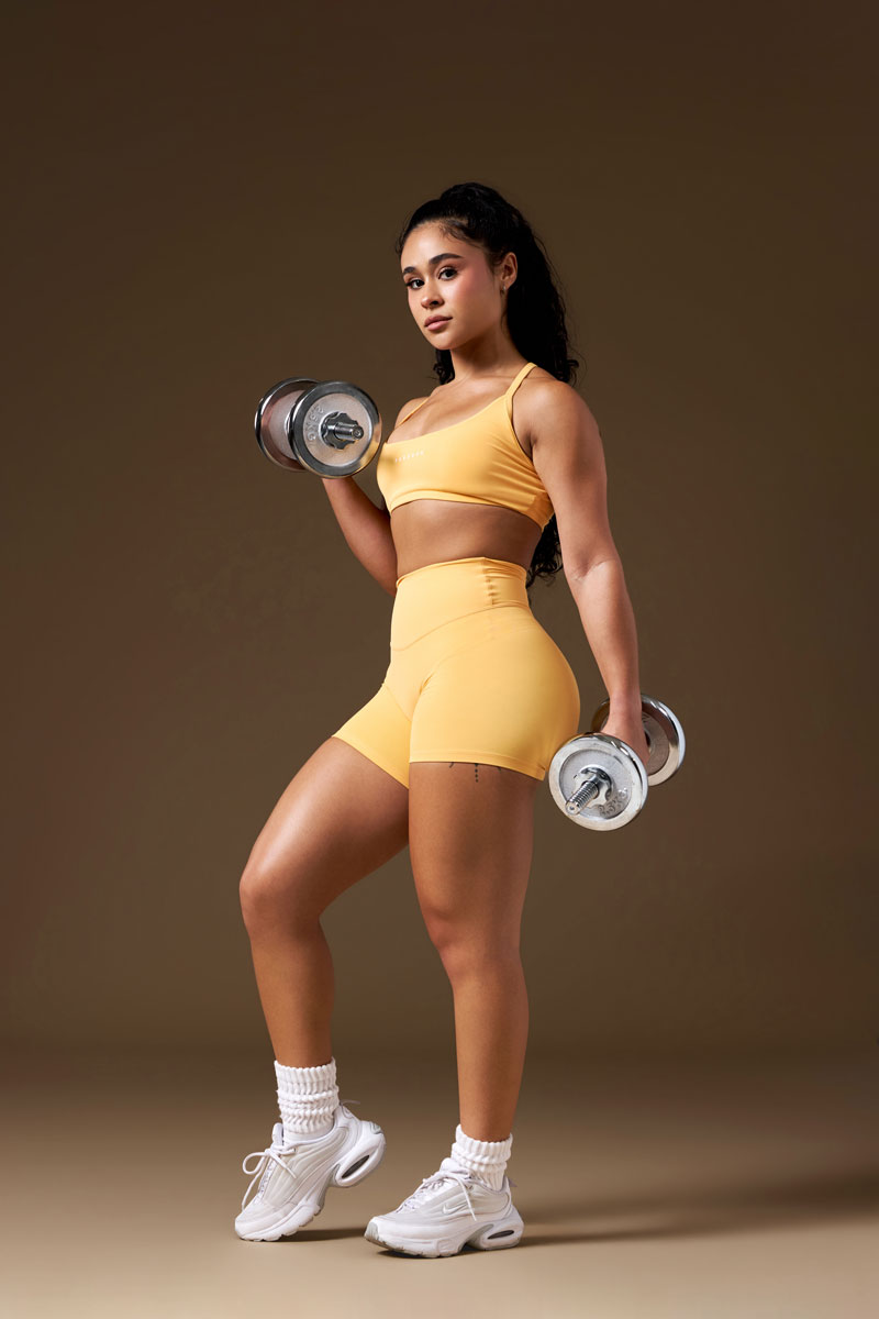 The coach is posing while holding the dumbelles.