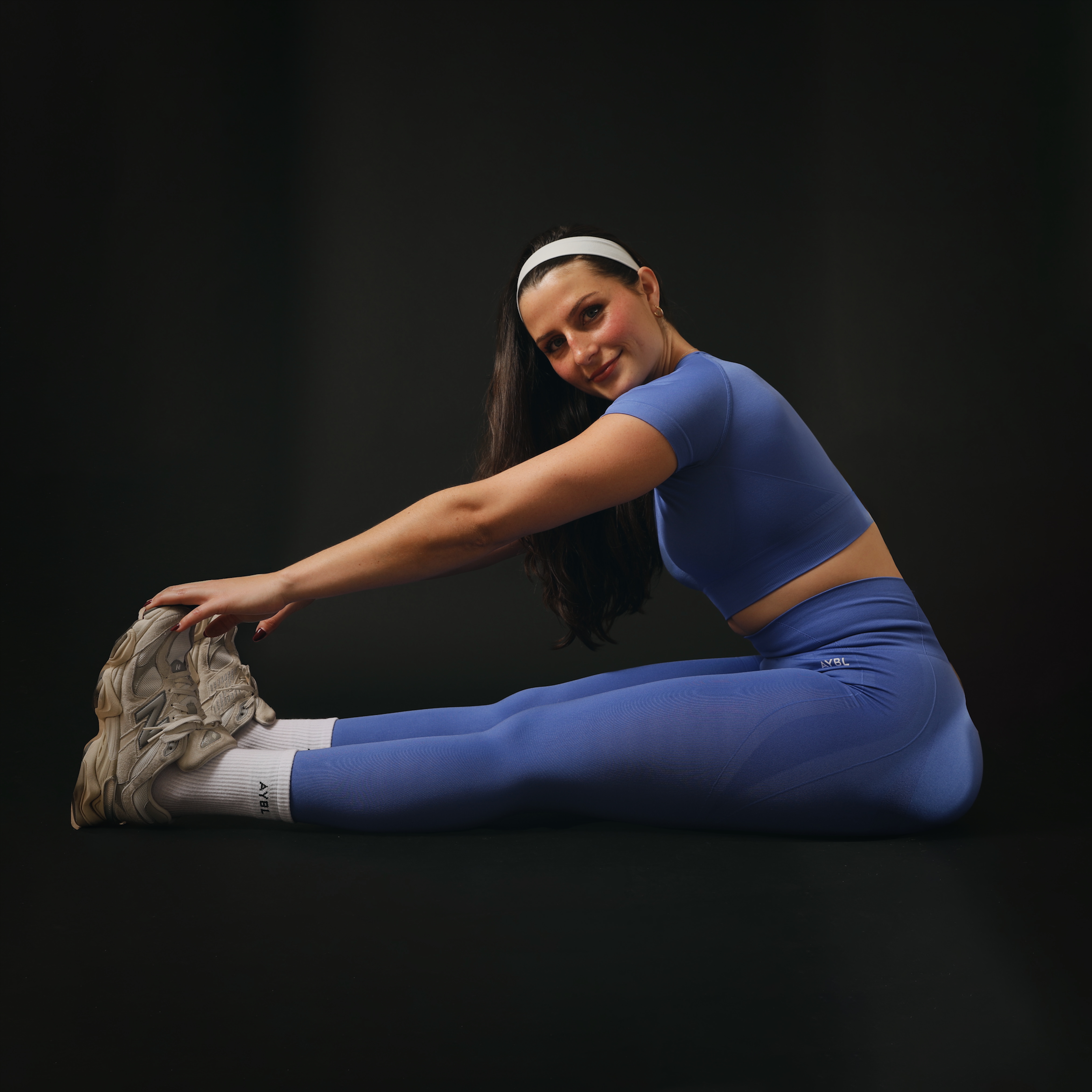 Coach is streching her legs wearing a blue wrokout outfit.