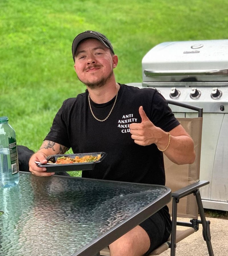 Coach is smiling to the camera while holding a food plate.
