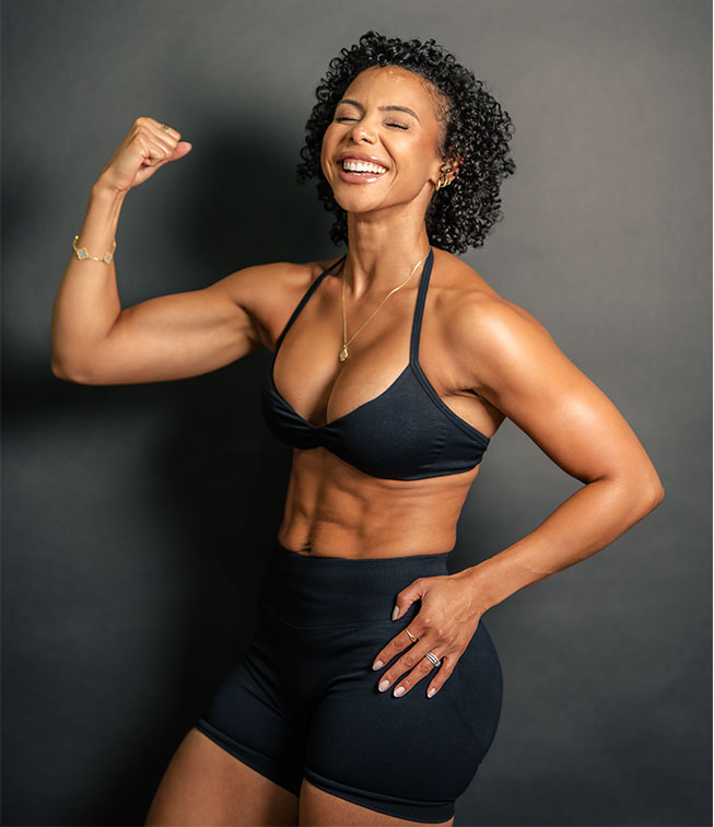 Coach Iza is smiling while flexing her bicep