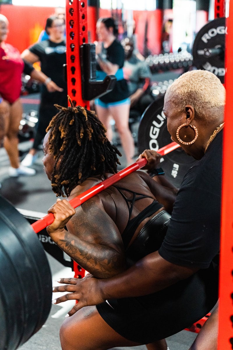 Coach is helping a client in the gym.