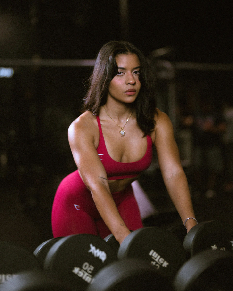 The coach is posing at the gym while bending her body.