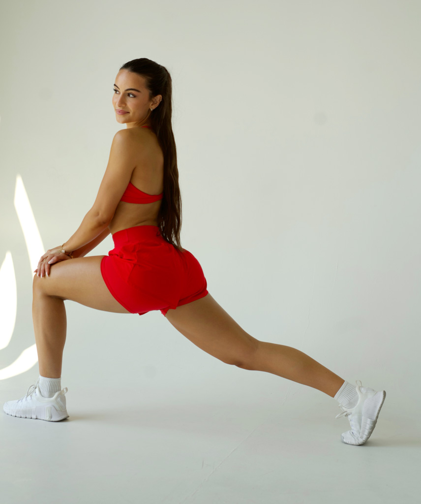 Coach is posing in a red workout outfit.