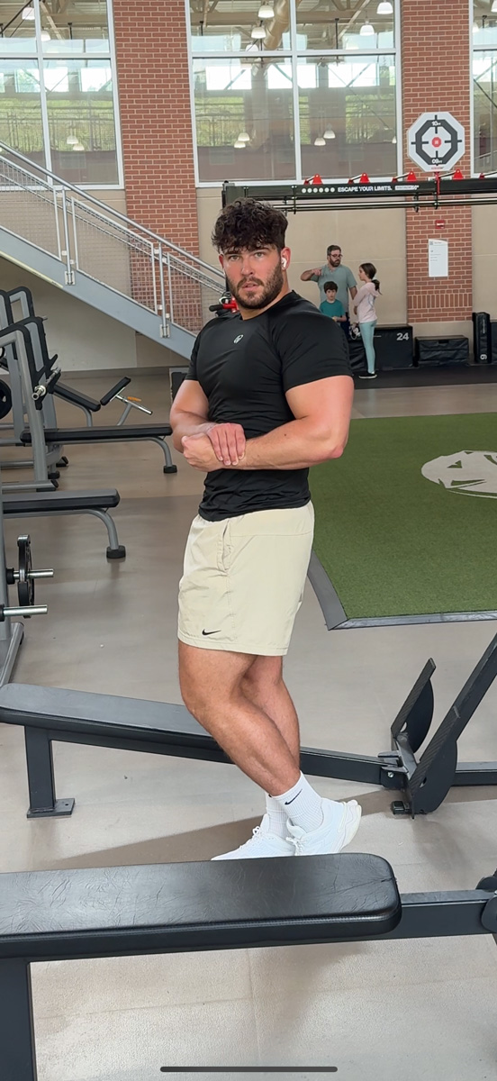 The coach is posing at the gym.