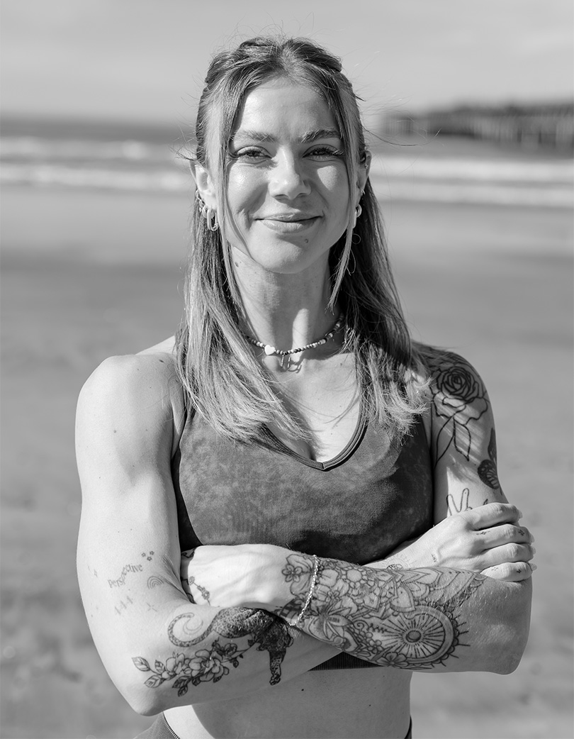 Coach at the beach, with her arms crossed.