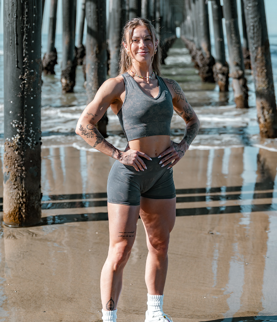 Coach posing at the beach, wearing workout clothes.