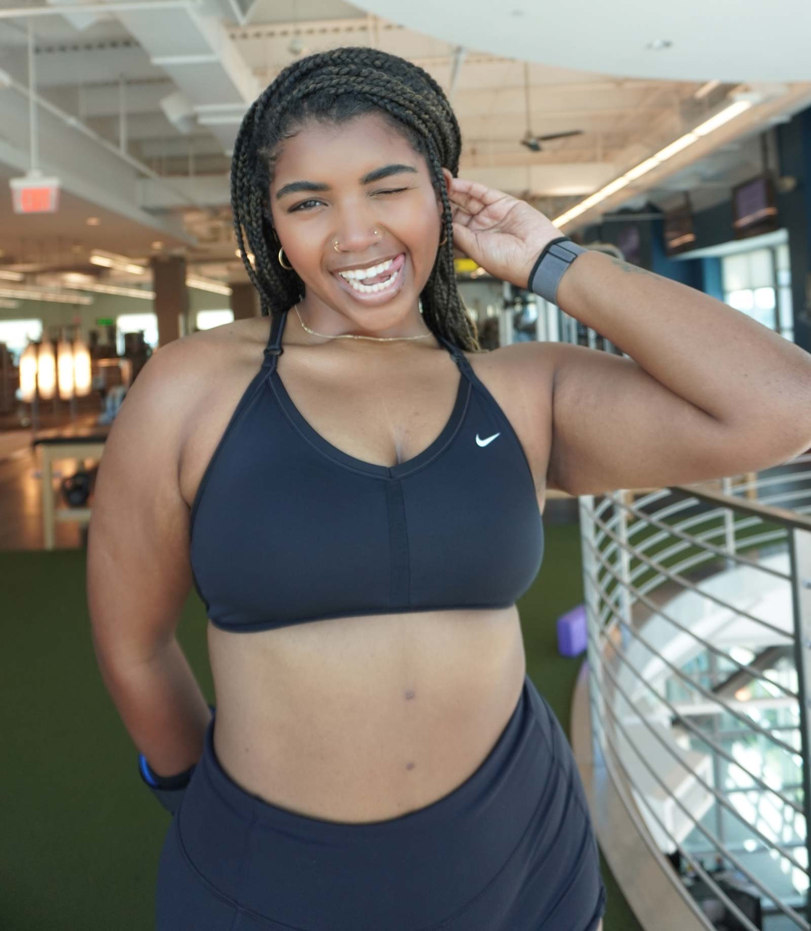 Coach smiling at the camera with a lively expression in a gym setting.
