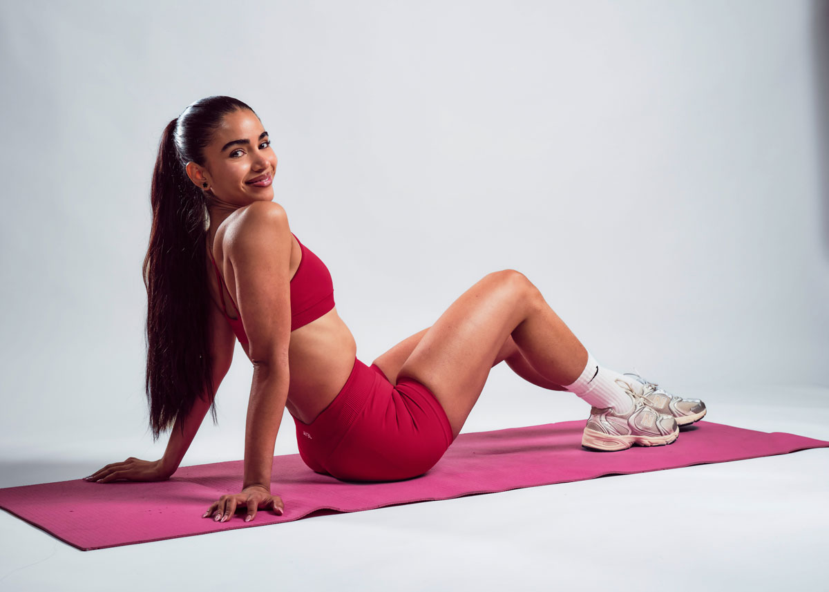 The coach is smiling while posing excercise.