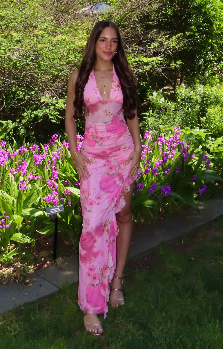 The coach is smiling while wearing a pink dress.