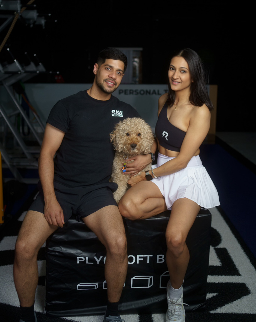 The coaches are posing with their dog in teh gym.