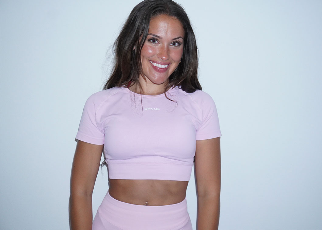 Coach smiling in light purple workout set against white background.