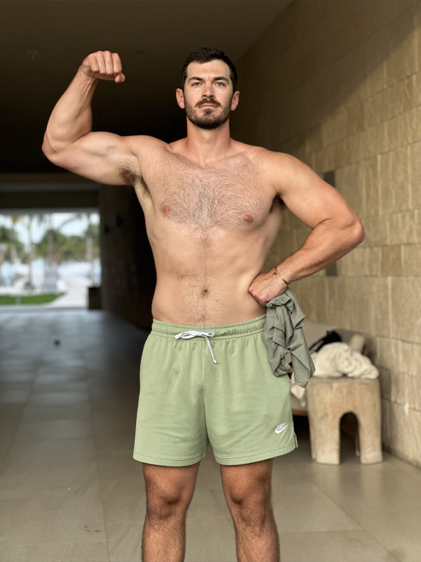 Coach is flexing his bicep while topless