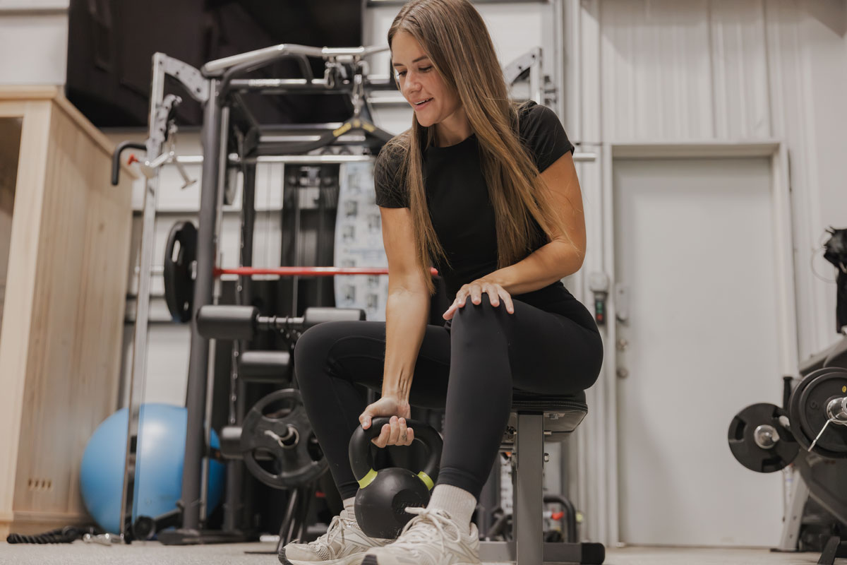 The coach is holding the kettlebell at the gym.