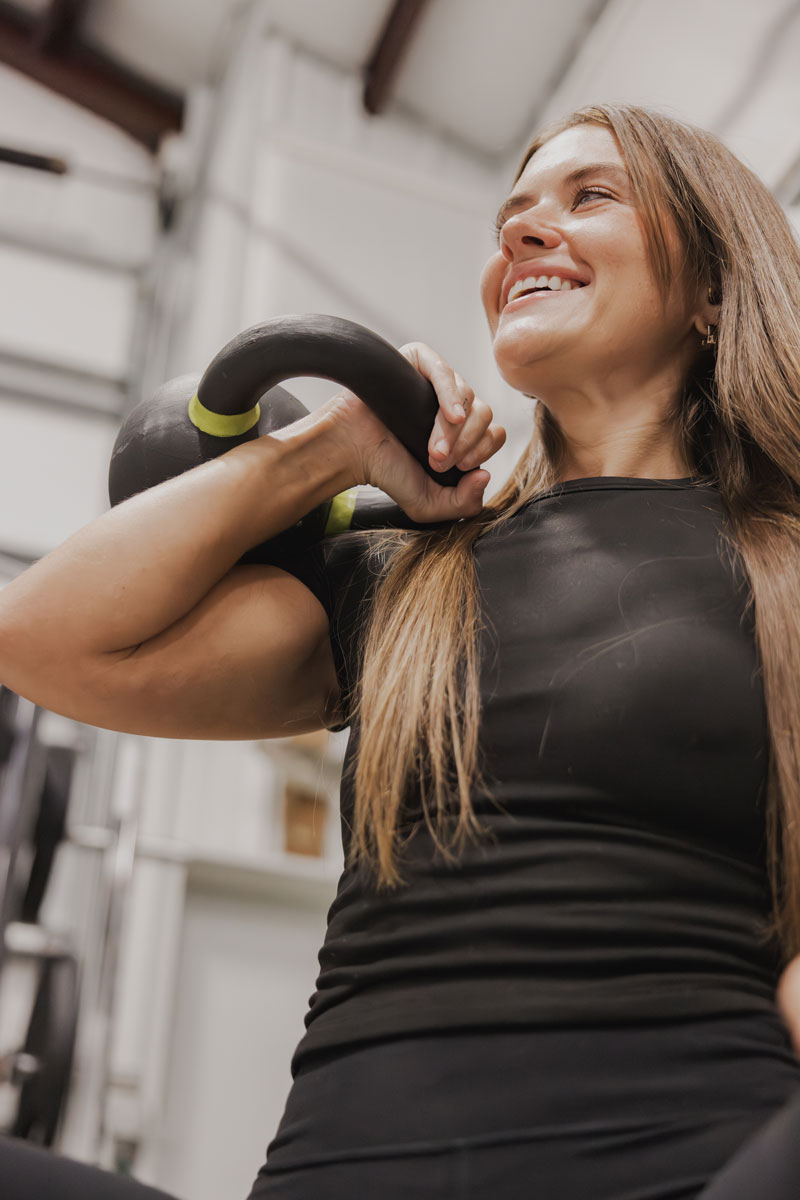 The coach is smiling while holding the kettlebell.